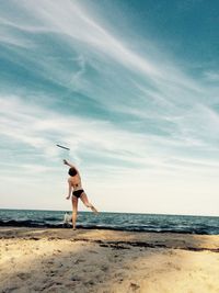 Woman standing at beach against sky