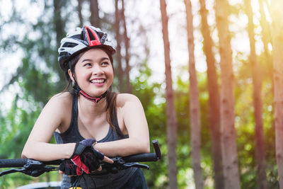 Portrait of smiling woman riding bicycle in forest