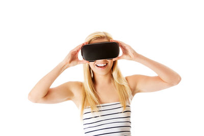 Smiling young woman wearing virtual reality simulator over white background