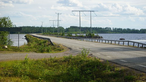 Empty road by river against sky