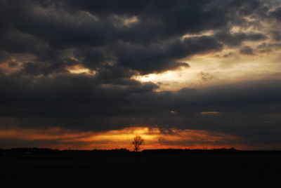 Scenic view of silhouette field against dramatic sky