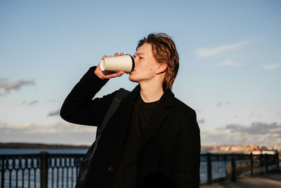 Young man drinking coffee while standing outdoors