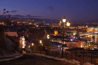 High angle view of illuminated street amidst buildings at night