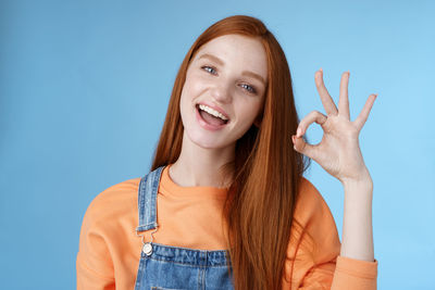 Portrait of smiling young woman against blue background