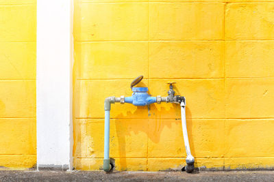 Close-up of yellow faucet against wall