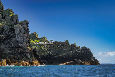 Rock formations by sea against blue sky