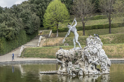 Statue by lake against trees