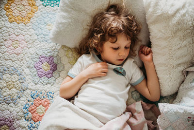 Overhead shot of young girl laying in bed watching tv