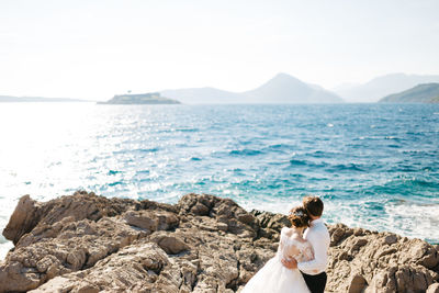 Couple standing by sea against sky