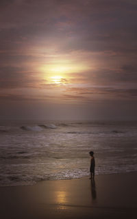 Silhouette man walking on beach against sky during sunset