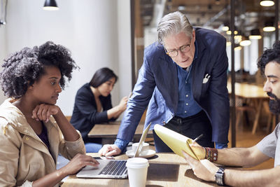 Business people working with female colleague sitting in background