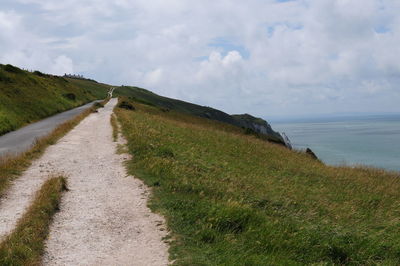 Scenic view of road by sea against sky