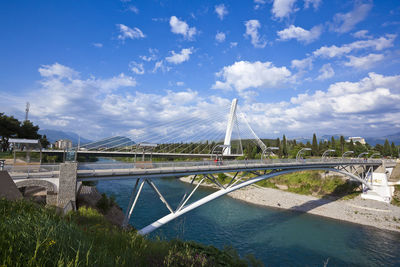 Bridge over river in city against sky