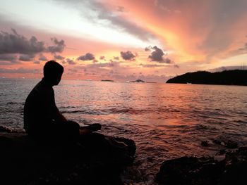 Silhouette man looking at sea against sky during sunset