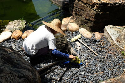 High angle view of men working on rock by lake