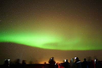 Blurred motion of people with aurora borealis in sky at night
