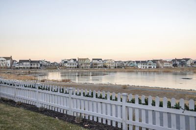 Buildings by river against clear sky during sunset