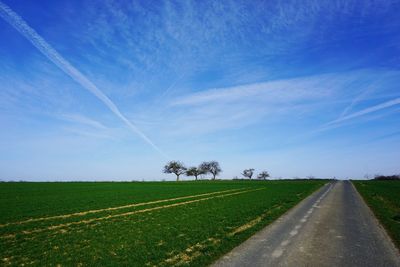 Road by landscape against blue sky