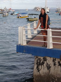 Portrait of smiling woman standing on pier by sea