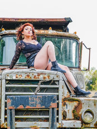 Portrait of young woman sitting on car