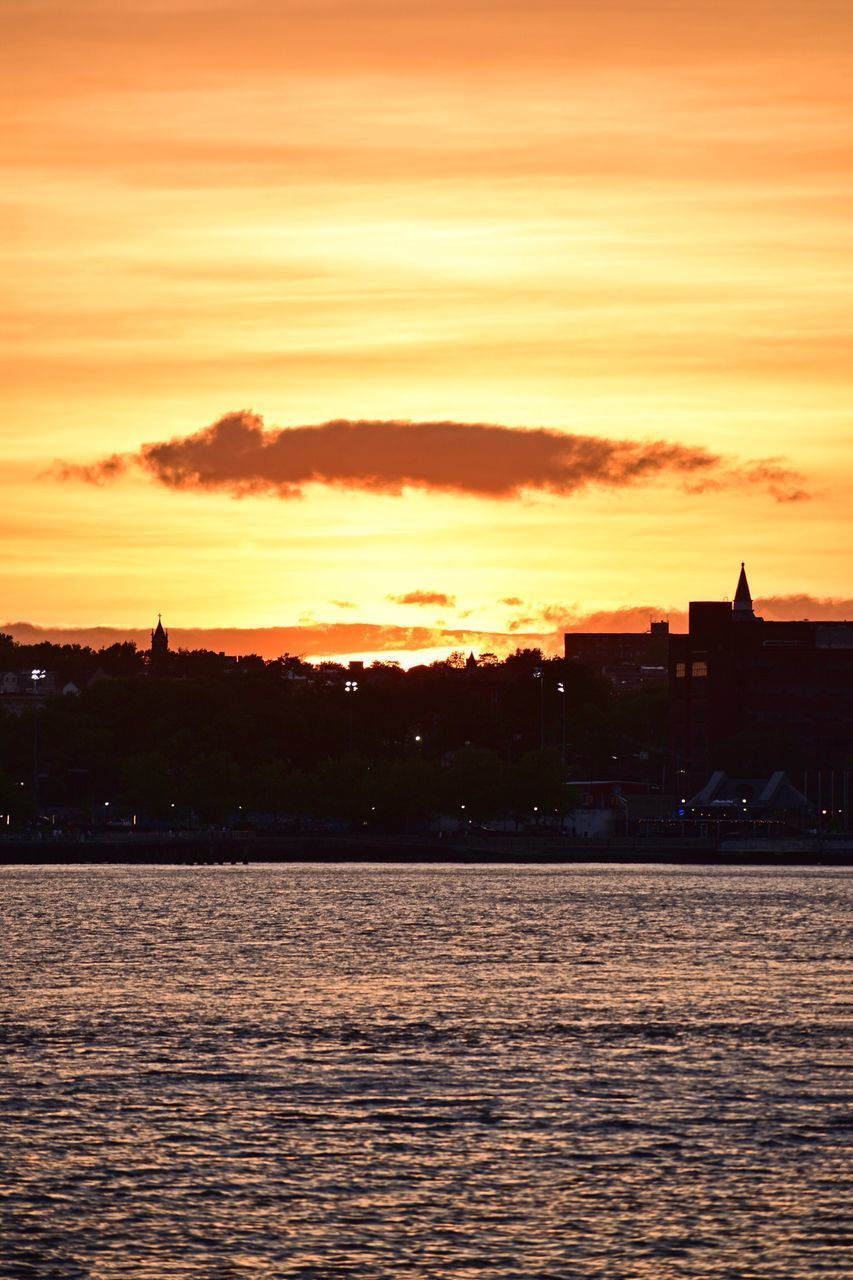 SILHOUETTE BUILDINGS BY SEA AGAINST ROMANTIC SKY