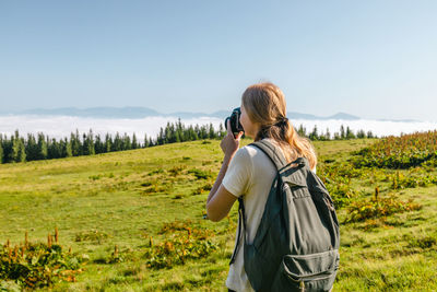 Rear view of woman standing on field against clear sky