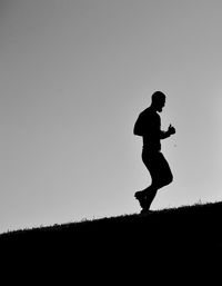 Silhouette man running on field against sky