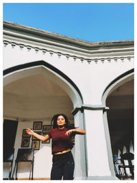 Portrait of a young woman standing against building