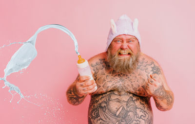 Portrait of young woman holding water against white background