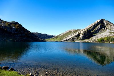 Scenic view of lake and mountains against clear blue sky