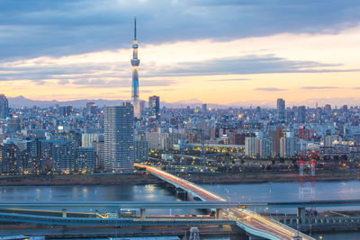 View of illuminated cityscape against cloudy sky