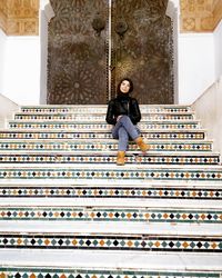 Full length portrait of woman sitting on staircase