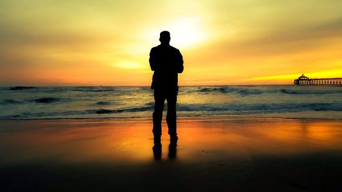 Silhouette man standing on beach during sunset