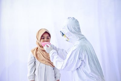 Man wearing protective suit and mask to cute girl against white background