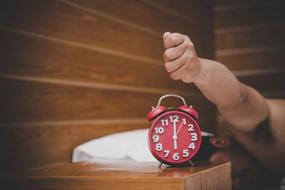 Man pressing alarm clock while relaxing on bed at home