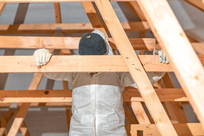 Rear view of man standing on wooden wall