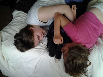 High angle view of sisters lying with dog on bed at home