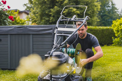 Man repairing lawn mower at yard