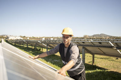 Young male maintenance engineer repairing solar panels at power station