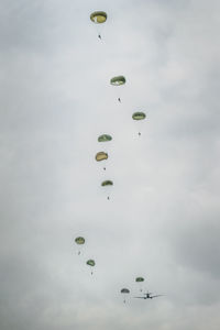 Low angle view of parachutes flying against sky