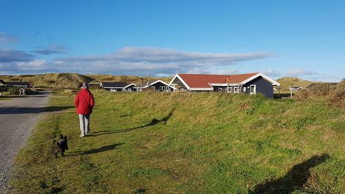 Rear view of senior woman walking on field against in town