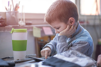 Boy using calculator while sitting at desk