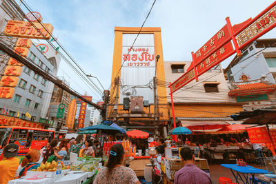 People on street market in city against sky