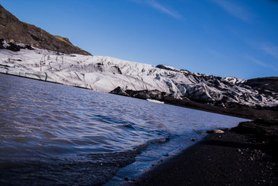 Scenic view of river by mountains against sky