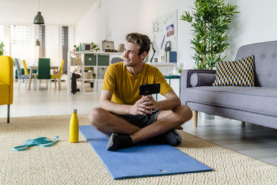 Young man using mobile phone while sitting on sofa at home