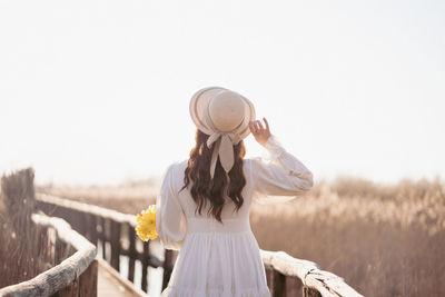Rear view of woman wearing hat standing against clear sky
