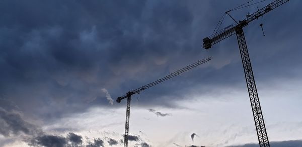 Low angle view of cranes against sky