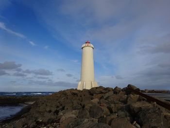 Lighthouse by sea against sky