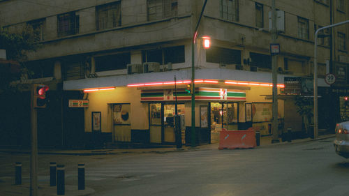 Illuminated street light against building at night