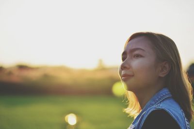 Close-up of young woman looking away against sky